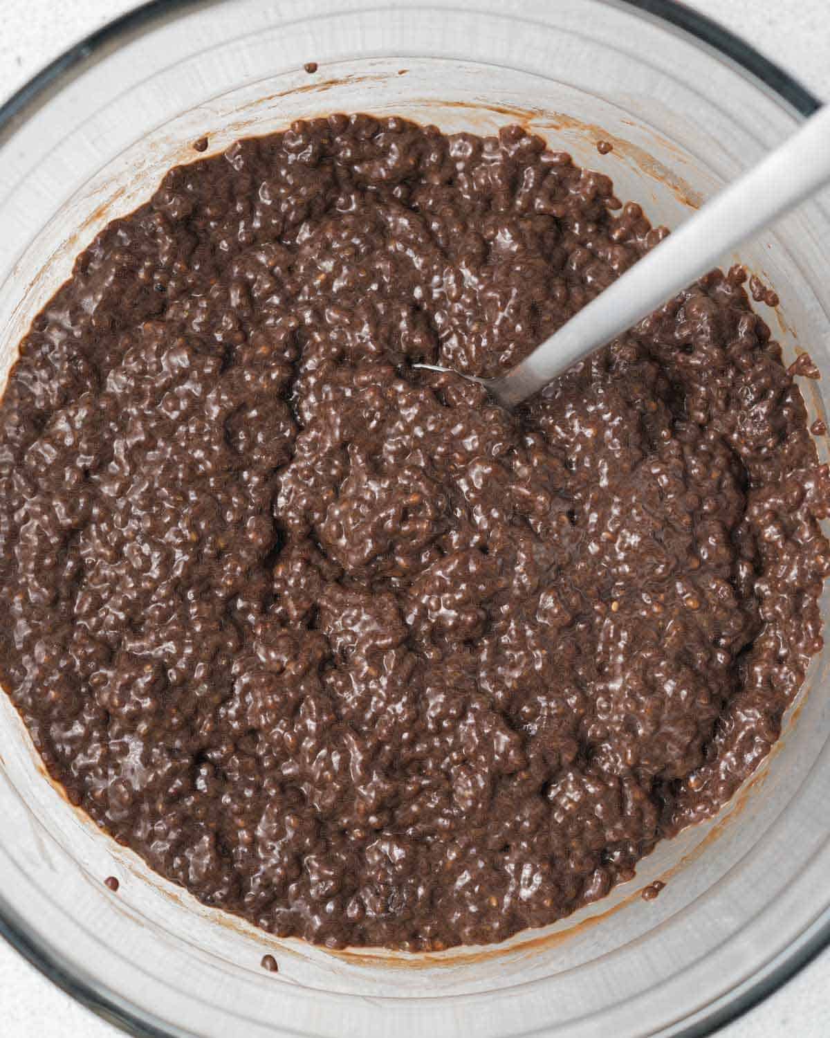 spoon mixing chia pudding in a clear bowl.