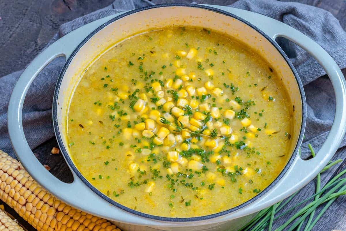corn chowder soup in a pot topped with fresh chives.