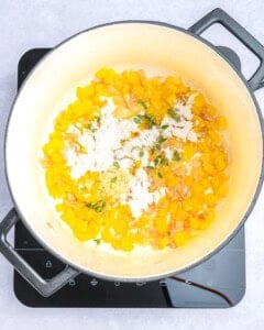 adding the flour and seasonings to sauteed veggies in a pot.
