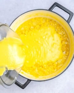 blended soup being added back into the pot with the corn chowder.