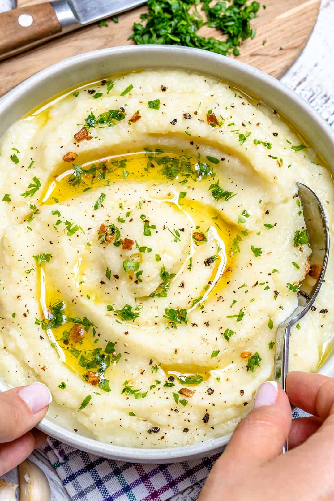 hand holding a spoon in a bowl with mash cauliflower
