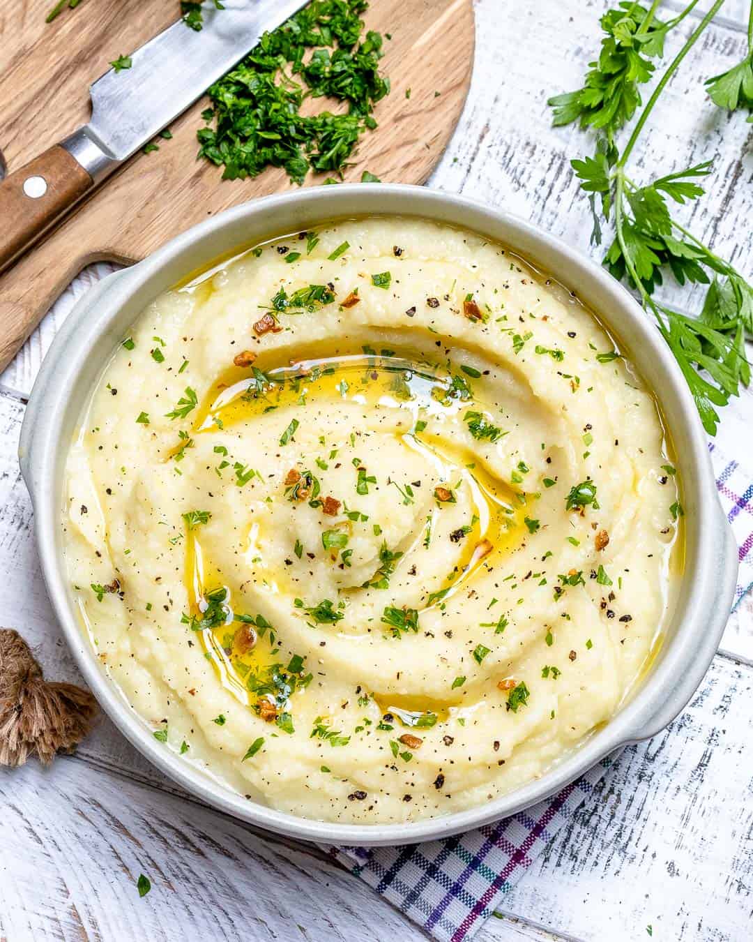 a bowl of cauliflower mash next to a cutting board