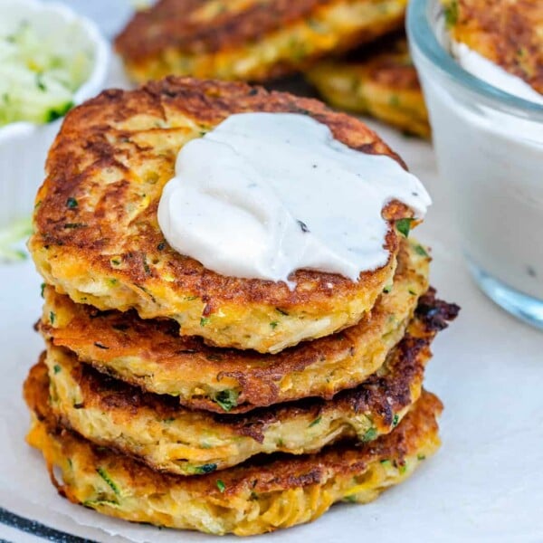 4 fritters stacked over each other on a plate topped with dressing.