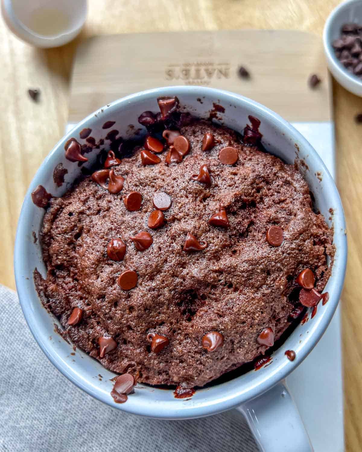 chocolate cake in a mug on a cutting board.