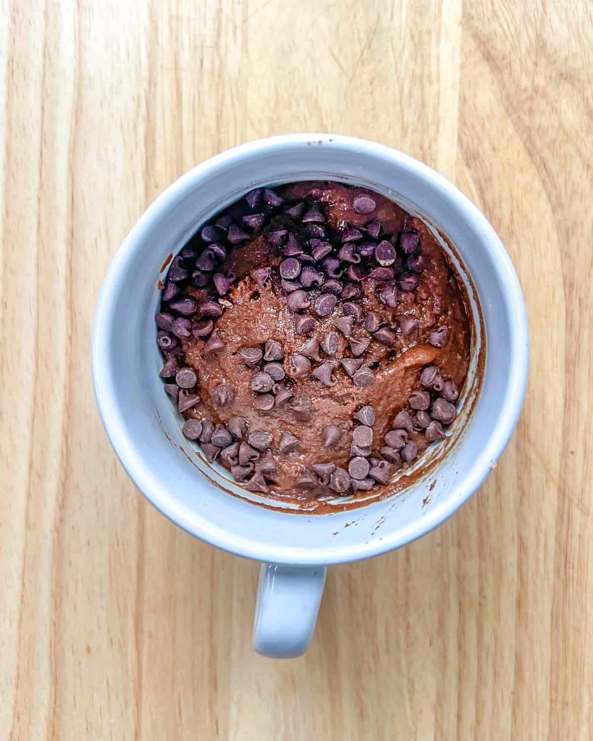 chocolate batter in a cup topped with chocolate chips.