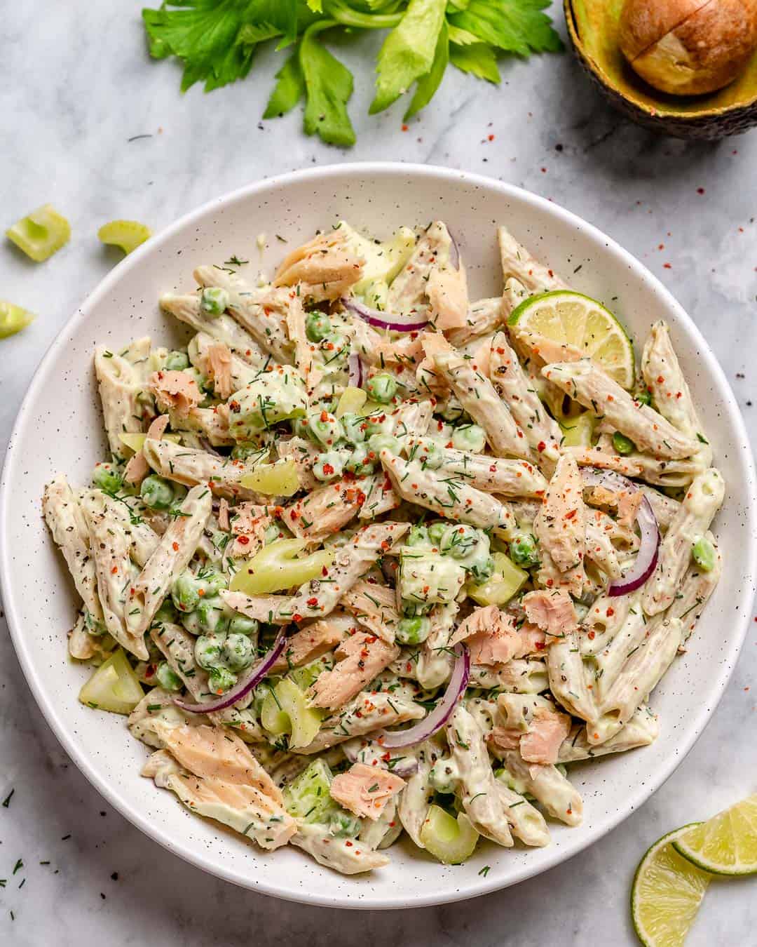 a round plate with tuna pasta salad topped with lime wedge and dill garnishes.