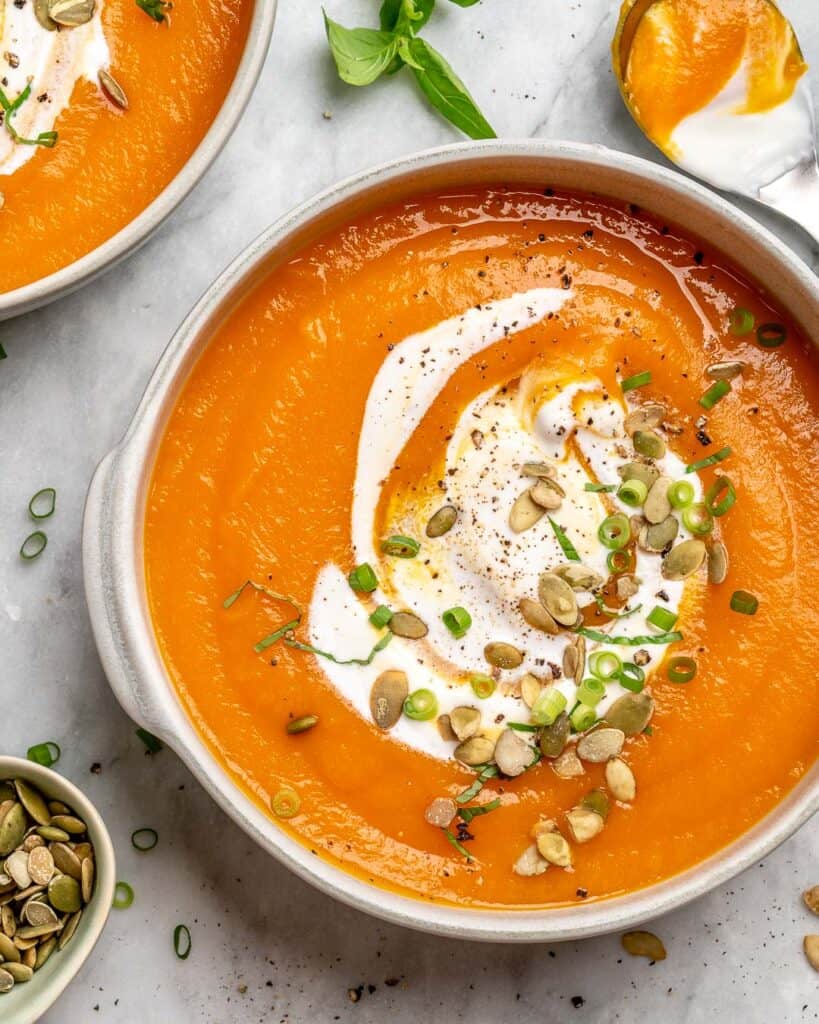 top view roasted pumpkin soup recipe in a white bowl topped with nuts