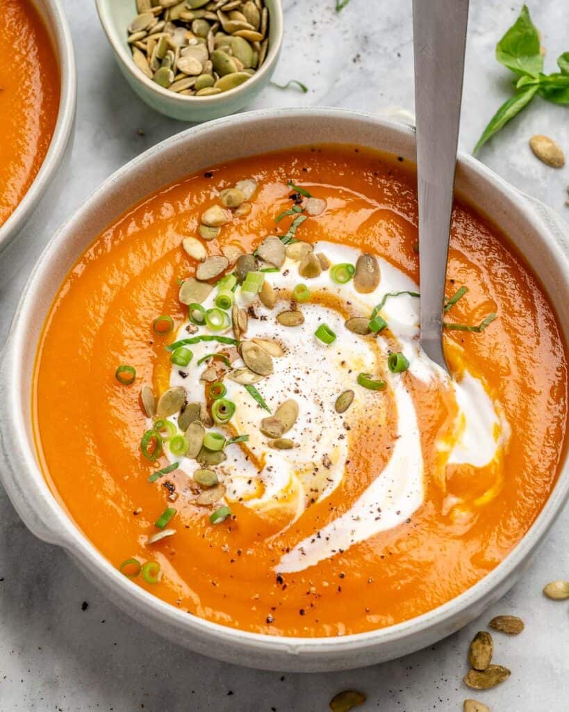 easy pumpkin soup in a white bowl with a spoon in the bowl