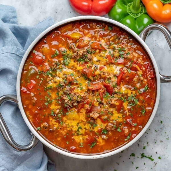 stuffed pepper soup in a round large pan with shredded cheese and chopped parsley.