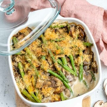 baked green bean casserole with mushroom and creamy sauce topped with crispy bread crumbs in a white dsh