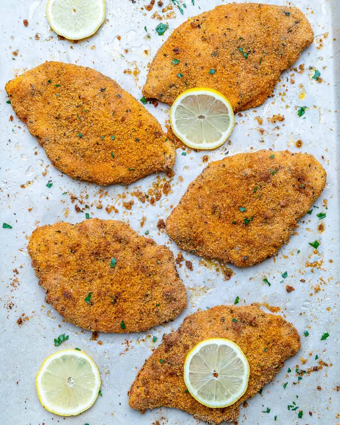 overhead view of baked chicken cutlets on a sheet pan