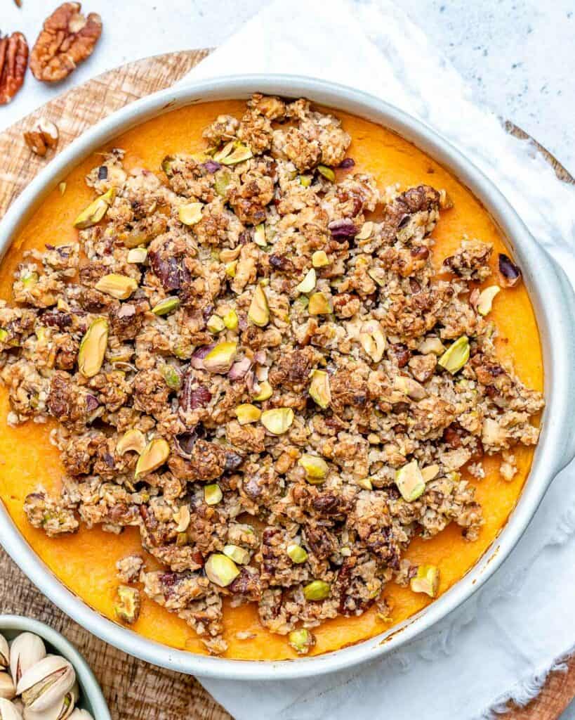 top view of sweet potato casserole in a white round dish with flour and sugary nuts topping