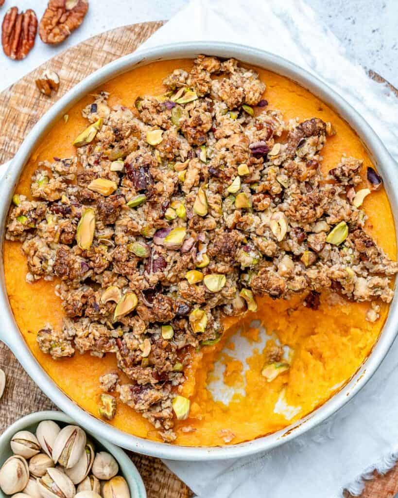 baked potato casserole in a round dish topped with an nut topping