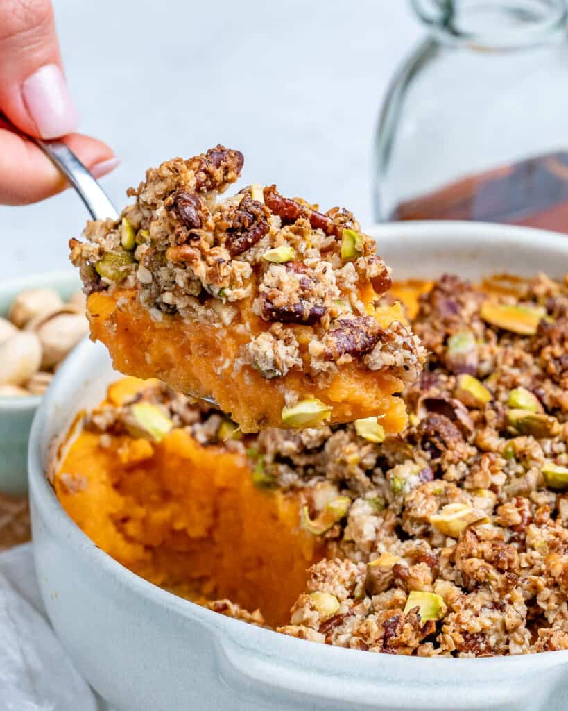 hand holding a spoonful of sweet potato casserole over a dish