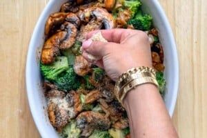 adding breadcrumbs over the top of the mushroom and broccoli in a dish.
