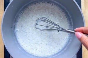 Whisking the milk mixture in a pot.