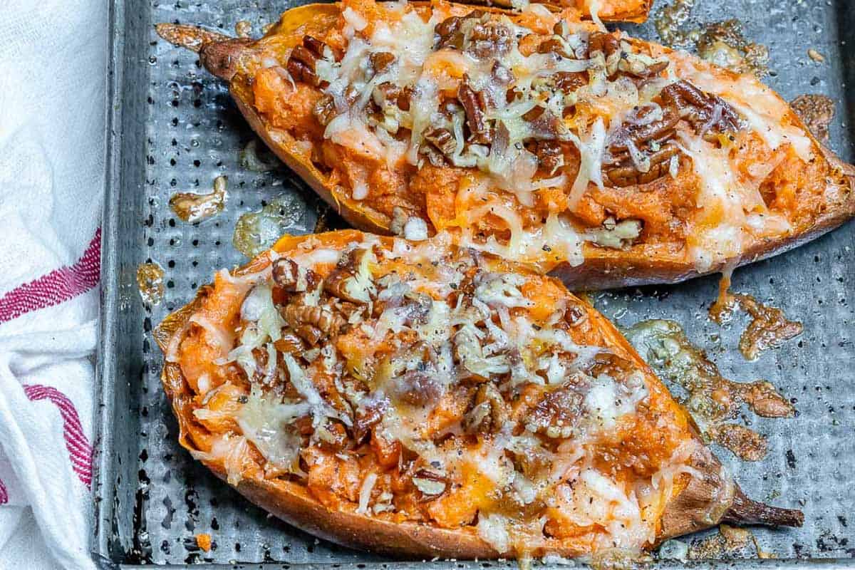 stuffed sweet potatoes with cheese and pecans on a pan.