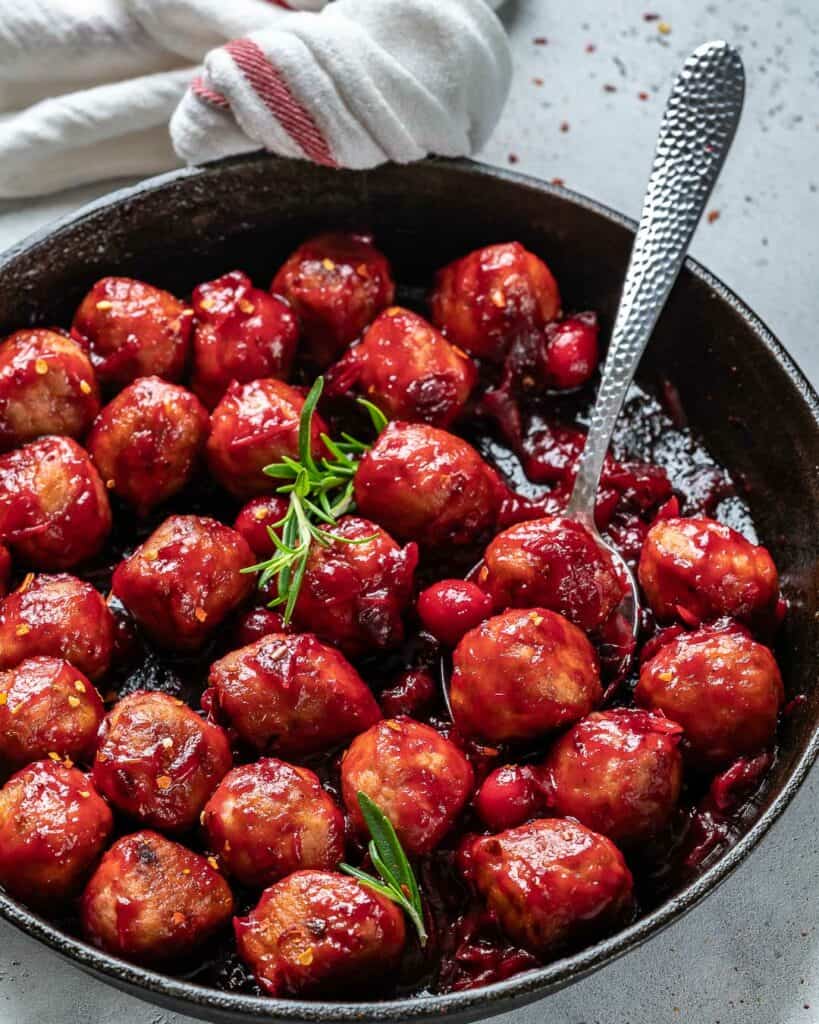 side shot of cranberry chicken meatball in a black skillet