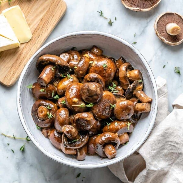 sauteed mushrooms in a round white bowl topped with fresh herbs