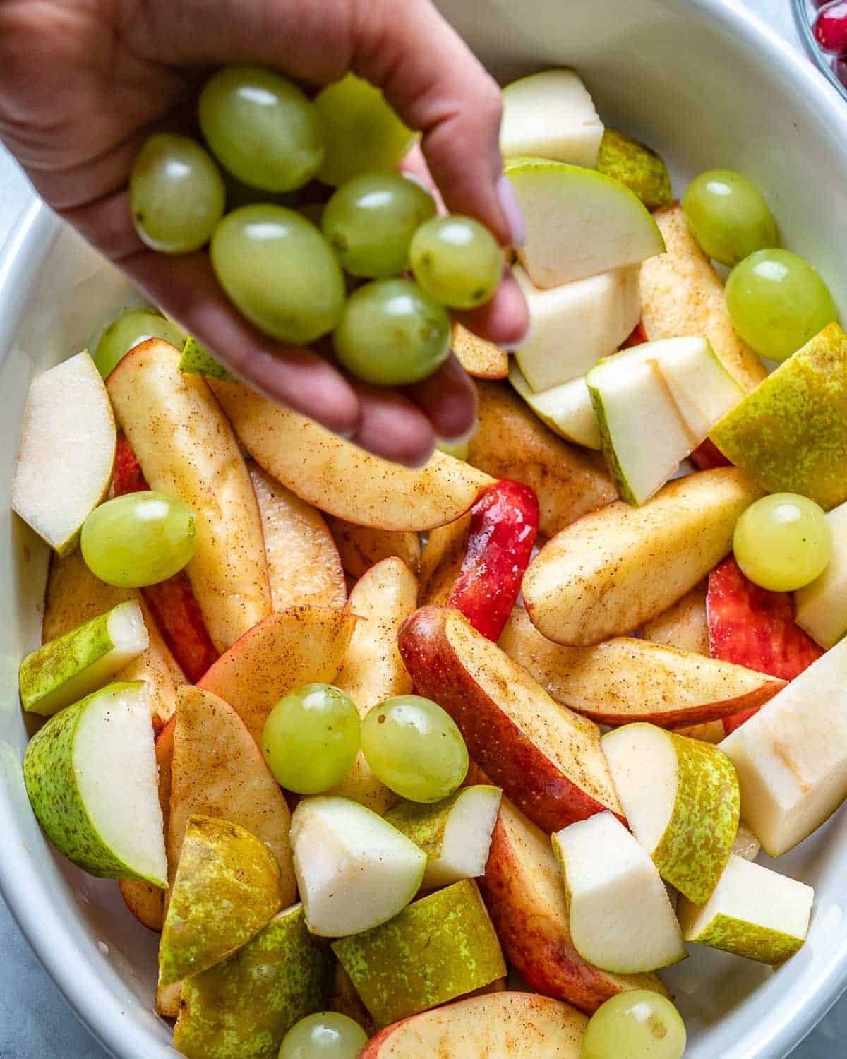 adding fruits coated in cinnamon in a dish.