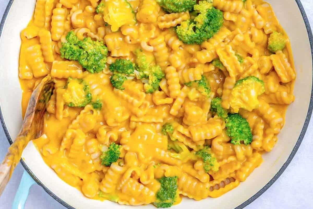 vegan macaroni and cheese in a skillet with broccoli florets.