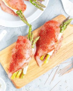 chicken breasts stuffed chicken asparagus, cheese, and sun-dried tomatoes on a cutting board. Before baking.