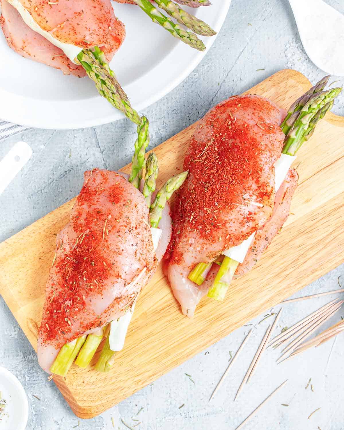 chicken breasts stuffed chicken asparagus, cheese, and sun-dried tomatoes on a cutting board. Before baking.