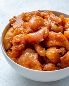 marinated raw chicken chunks in a round white bowl.