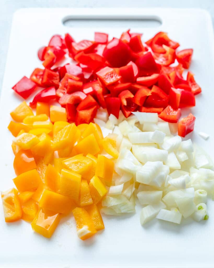 chopped yellow bell peppers, red bell peppers, and onions on a cutting board