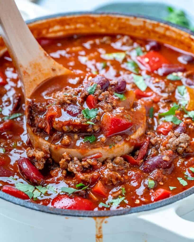 side view of a spoonful of beef chili in a pot