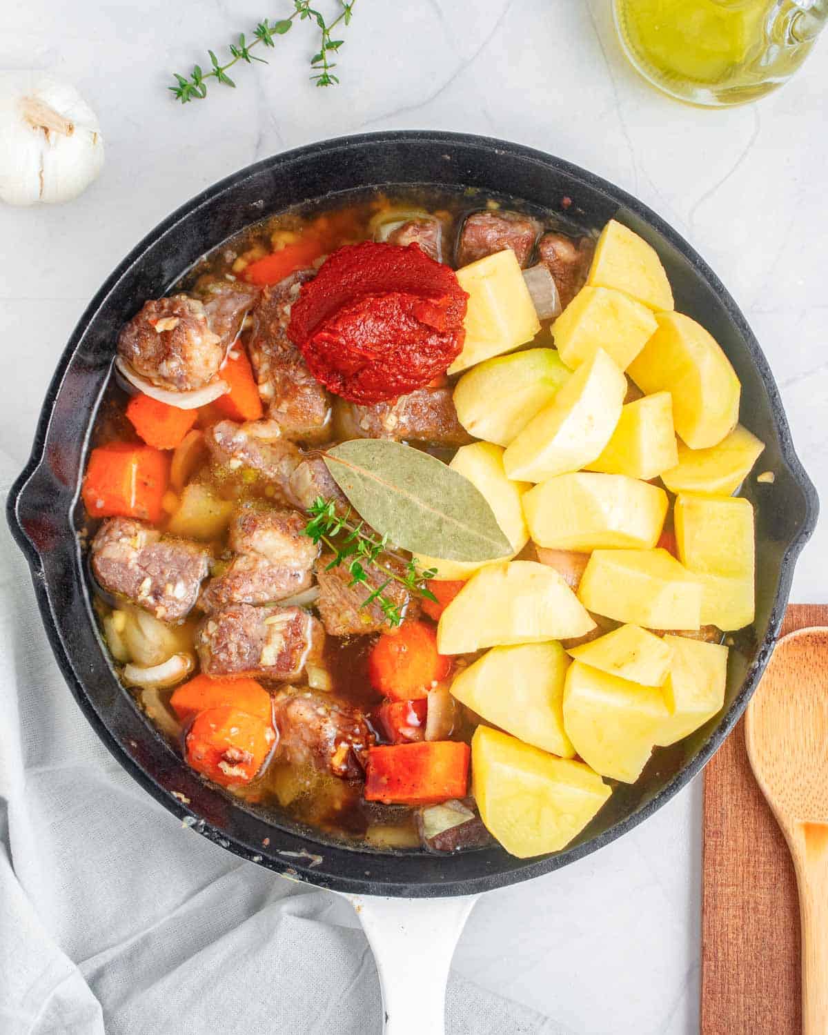   chopped potatoes and and tomato paste added over the seared beef.