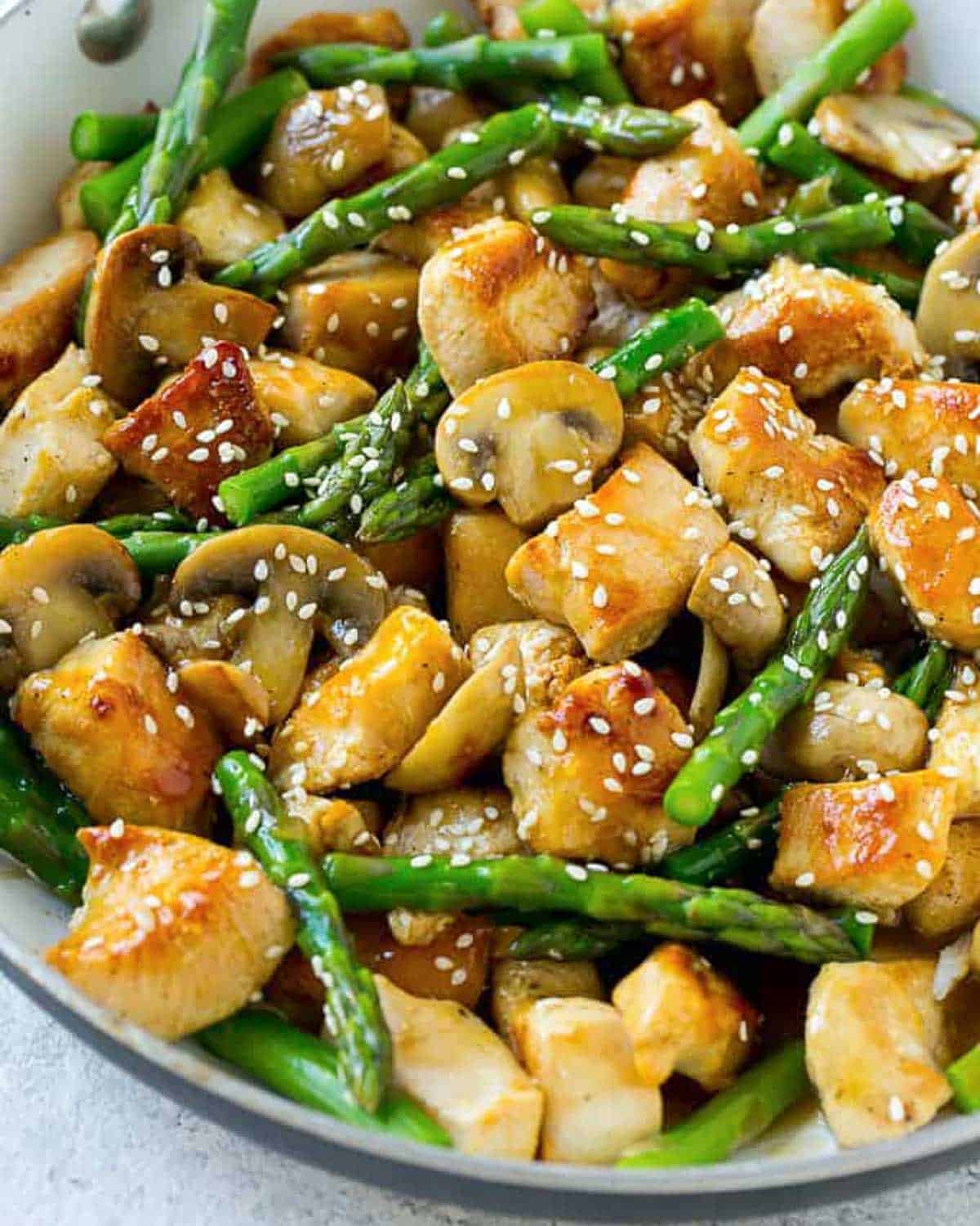 chicken and asparagus stir fry in a skillet.