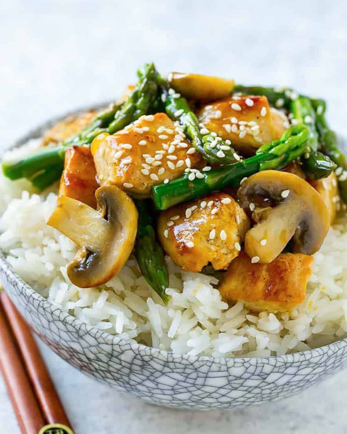 rice in a bowl topped with a chicken and asparagus stir fry.