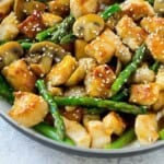 a skillet with chicken and asparagus stir fry.