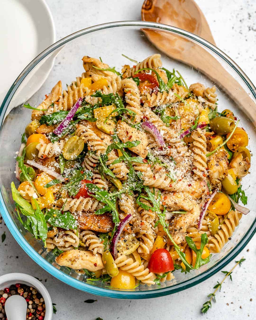 a round clear bowl with chicken pasta salad.