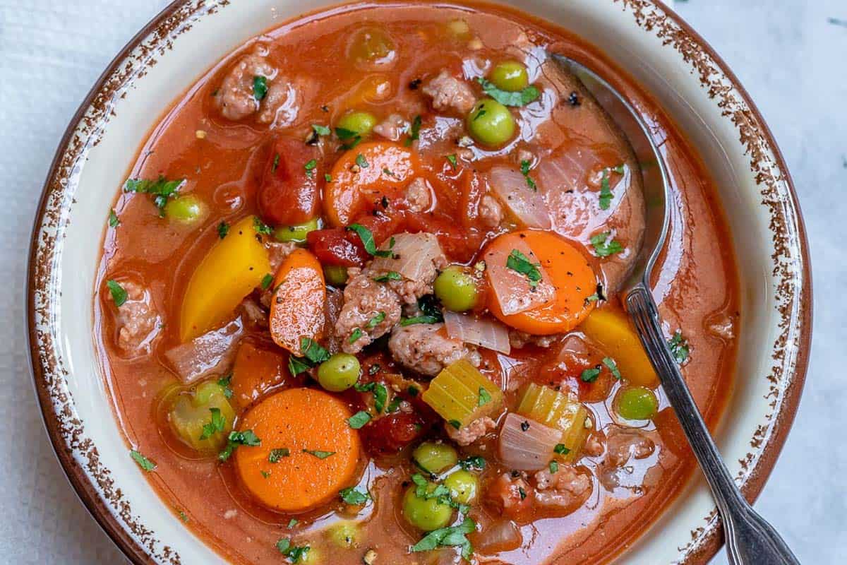 A spoon in a bowl of hamburger soup.
