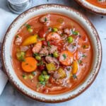 A bowl of hamburger soup with veggies.