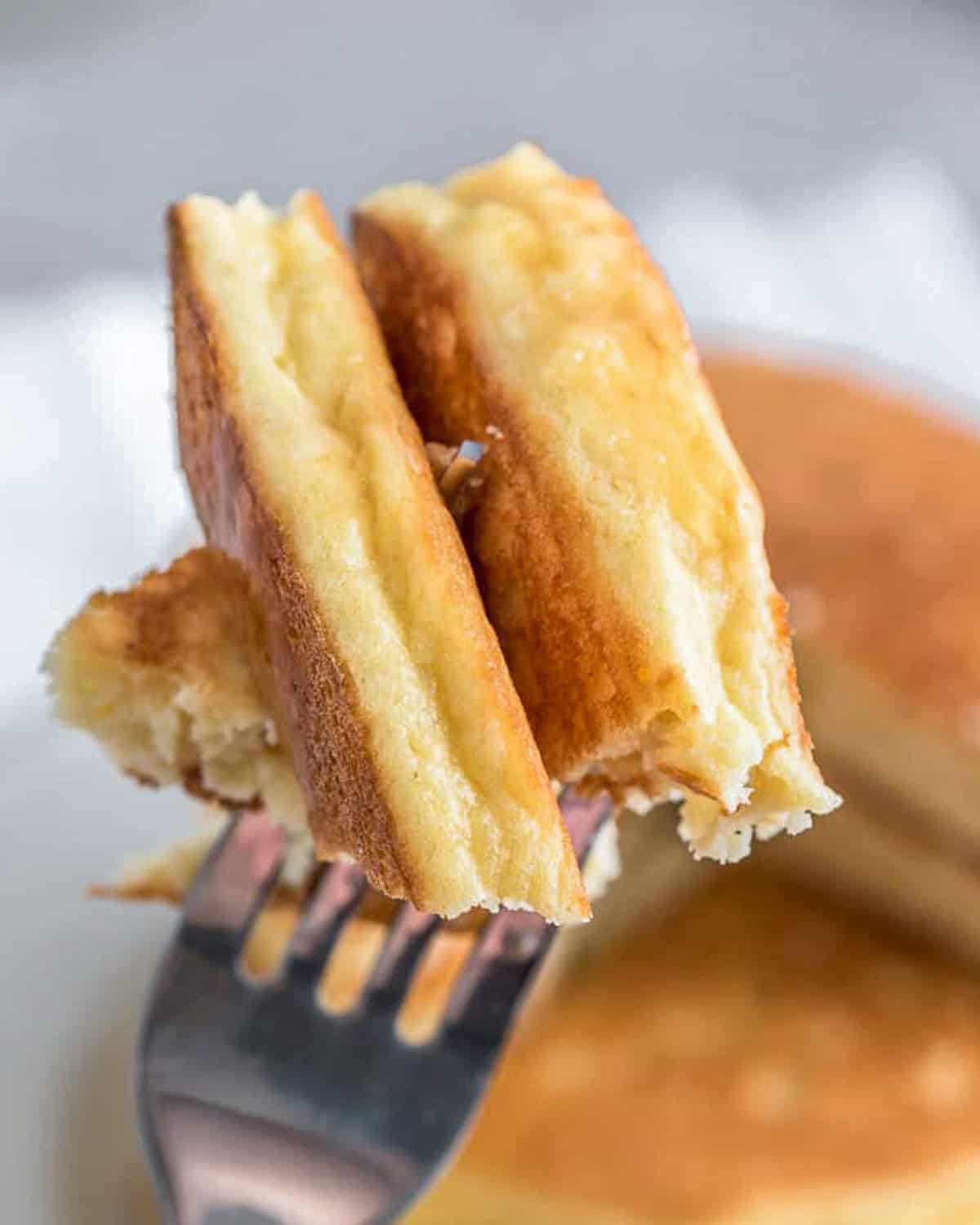 Fork holding two bites of pancakes.