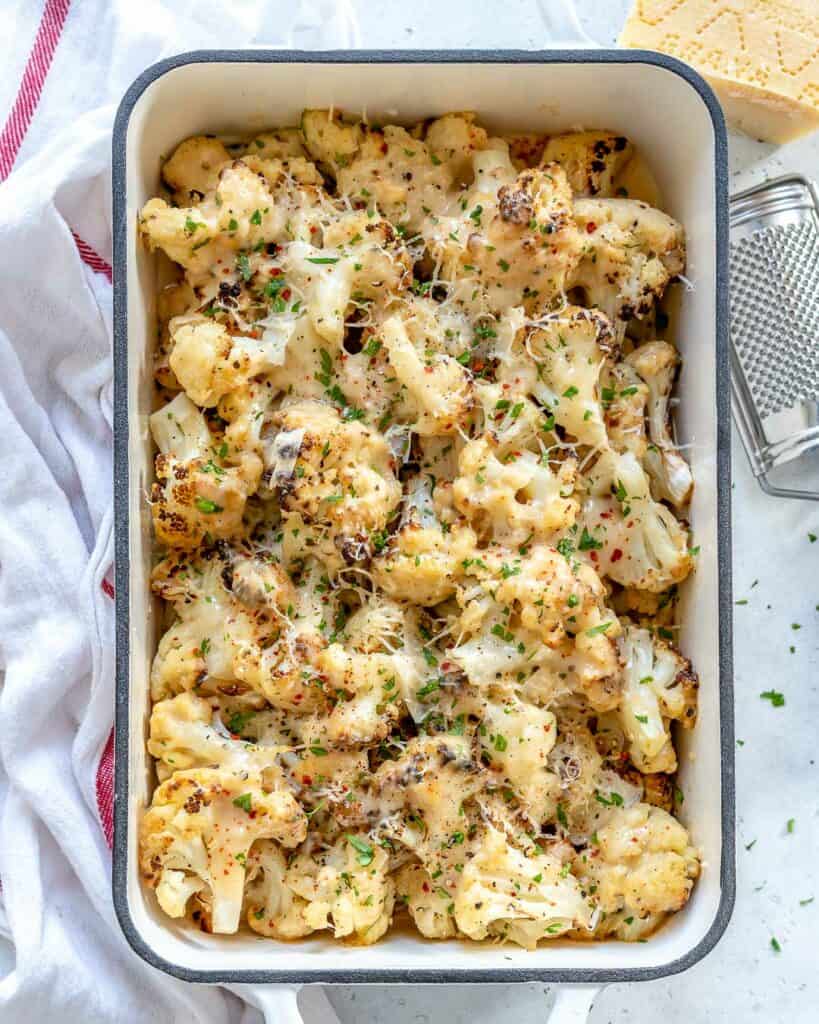 top view of a white baling dish with creamy and cheesy baked cauliflower florets 