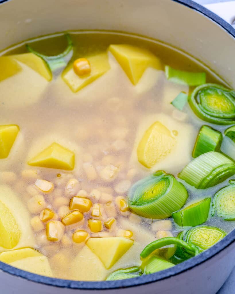 pot with broth, chopped potatoes, leeks, and corn, before boiling