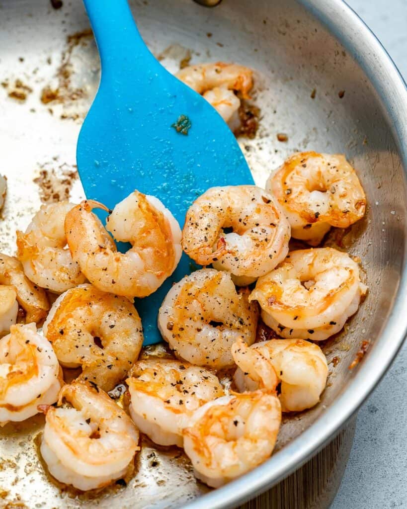 sauteed cooked shrimp shrimp for soup in a pan with light blue plastic spatula in skillet