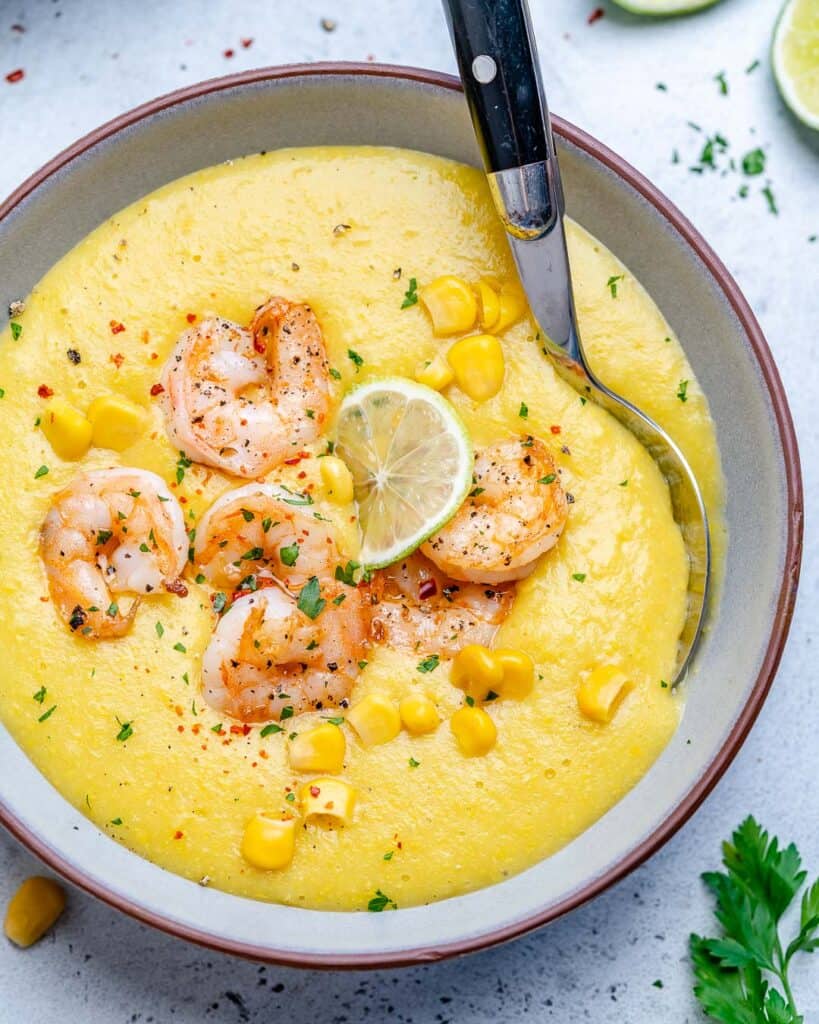 top view of spoon in a bowl or potato soup topped with sauteed shrimp and lime wedge 