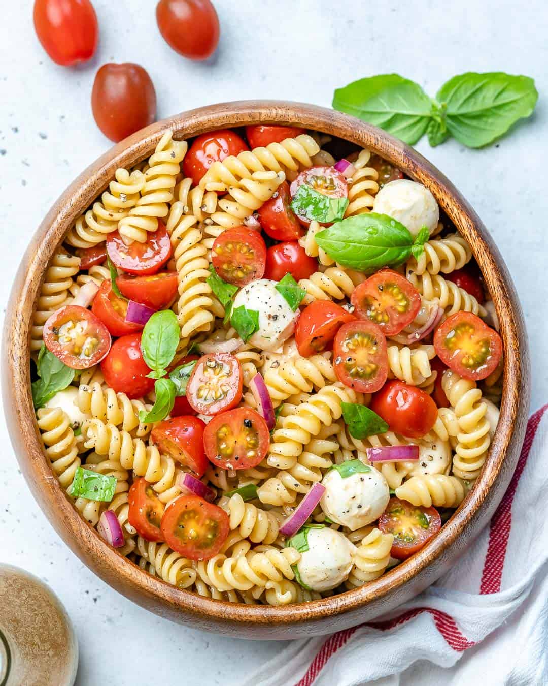 Caprese pasta salad in a round wooden bowl.