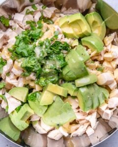 chopped chicken, sliced avocados, eggs, and dressing added to a bowl.