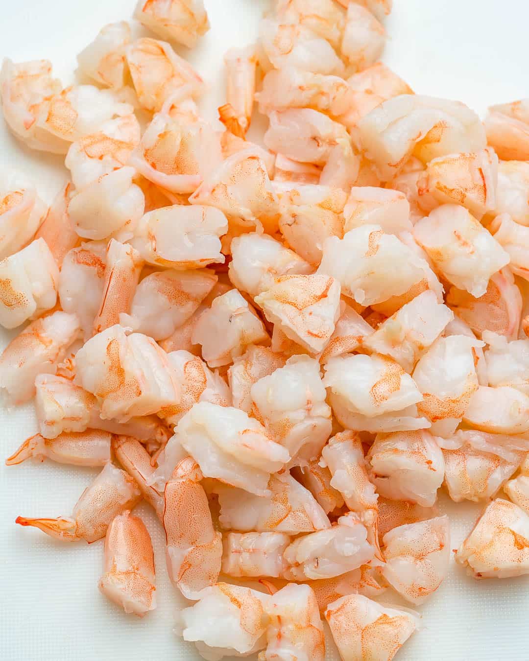 chopped shrimp into bite sizes on a cutting board.