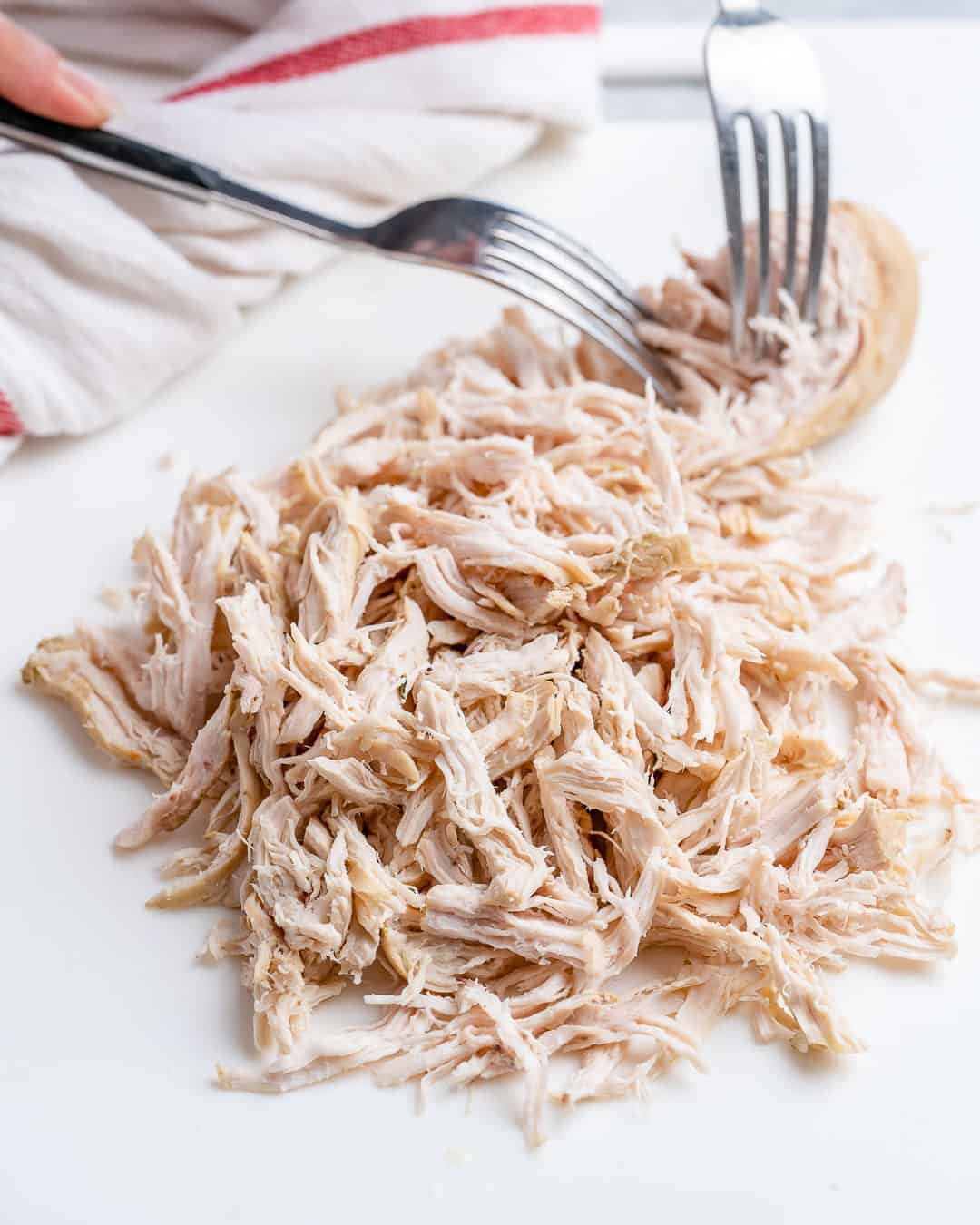 Poached chicken shredded on cutting board