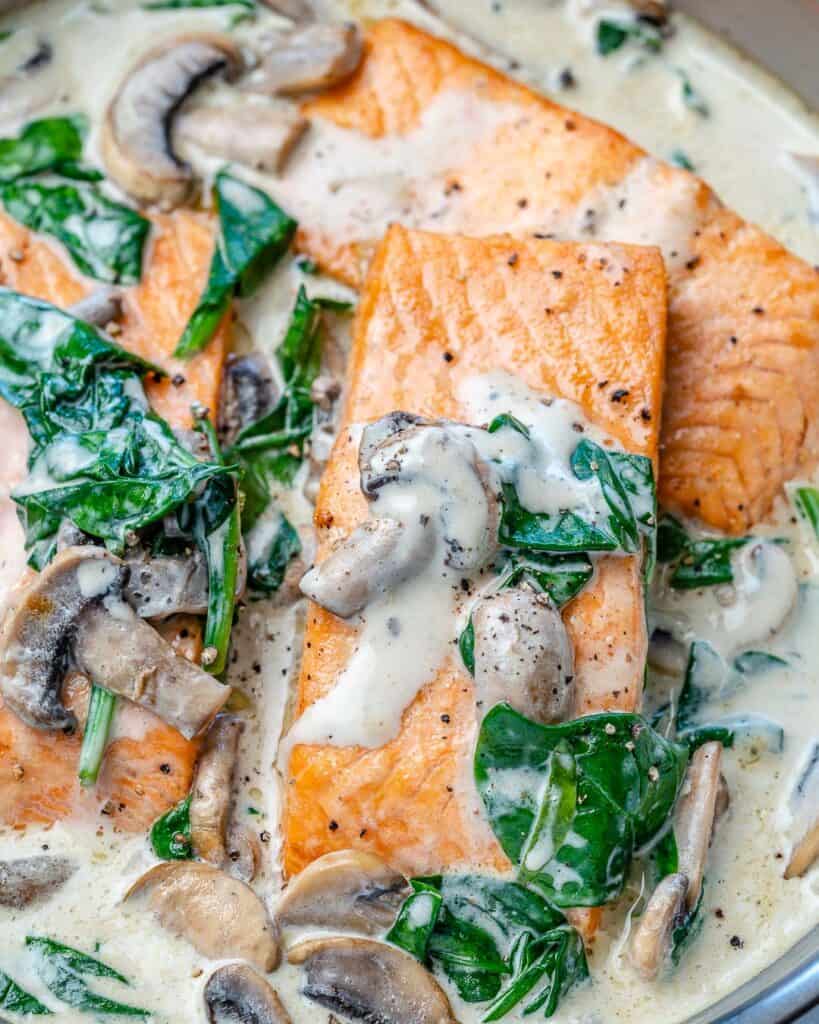 close up view of cooked salmon with creamy mushroom and spinach sauce