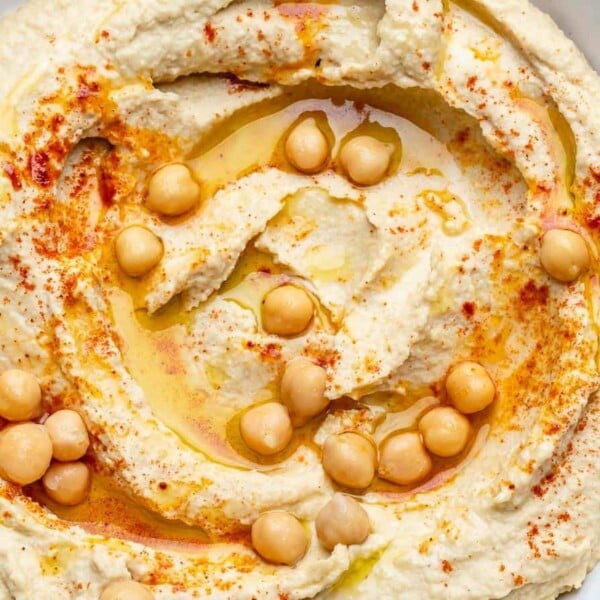 homemade hummus on a plate with a drizzle of olive oil and topped with chickpeas.