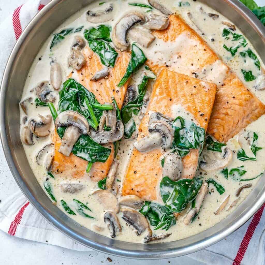 Salmon florentine recipe with spinach and mushrooms in a round silver pan