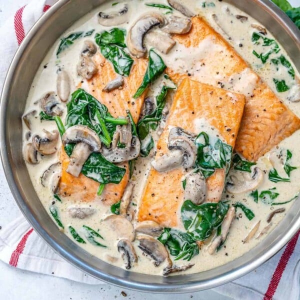 Salmon florentine recipe with spinach and mushrooms in a round silver pan.